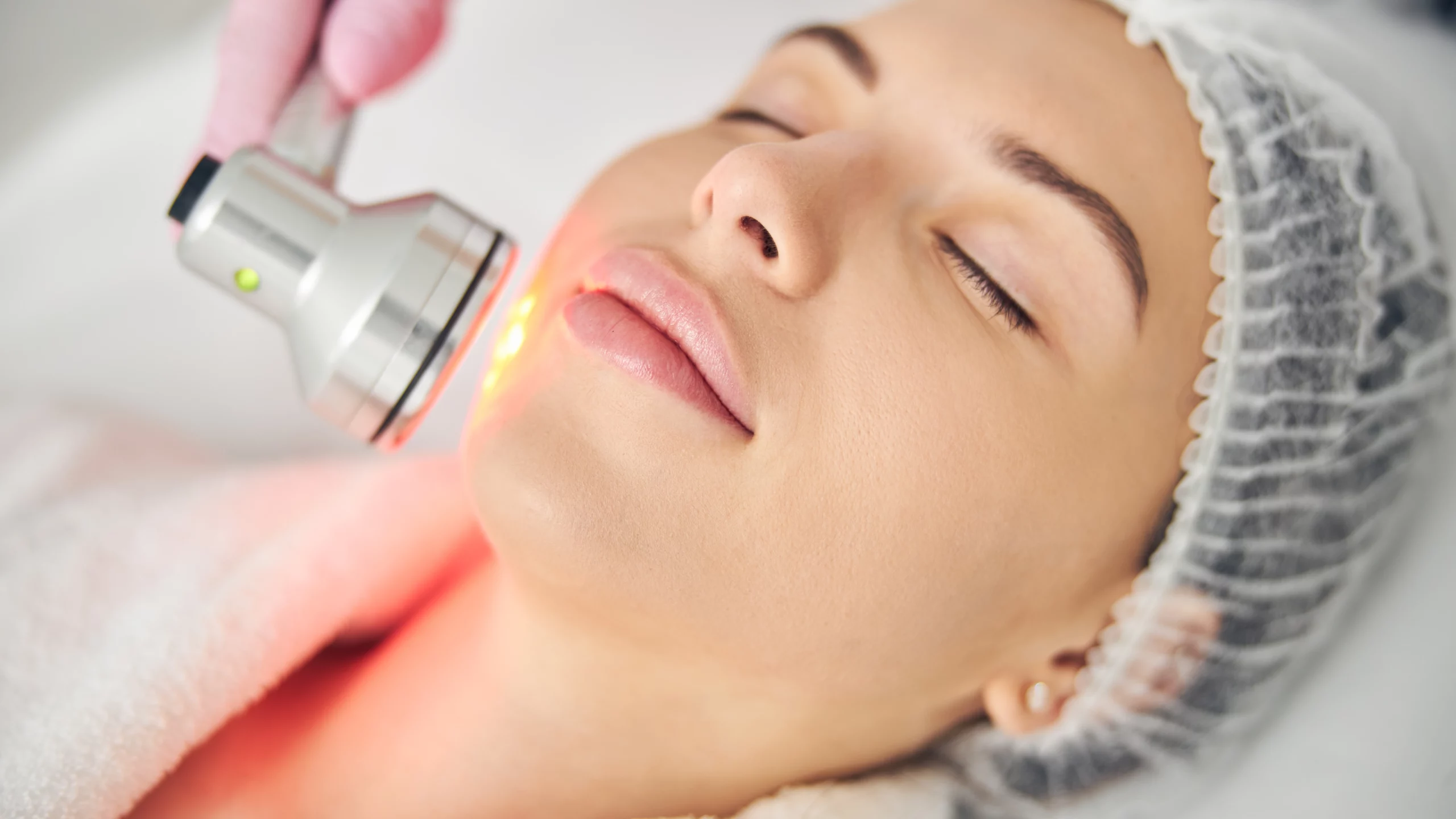 Young woman getting red light therapy on her face.