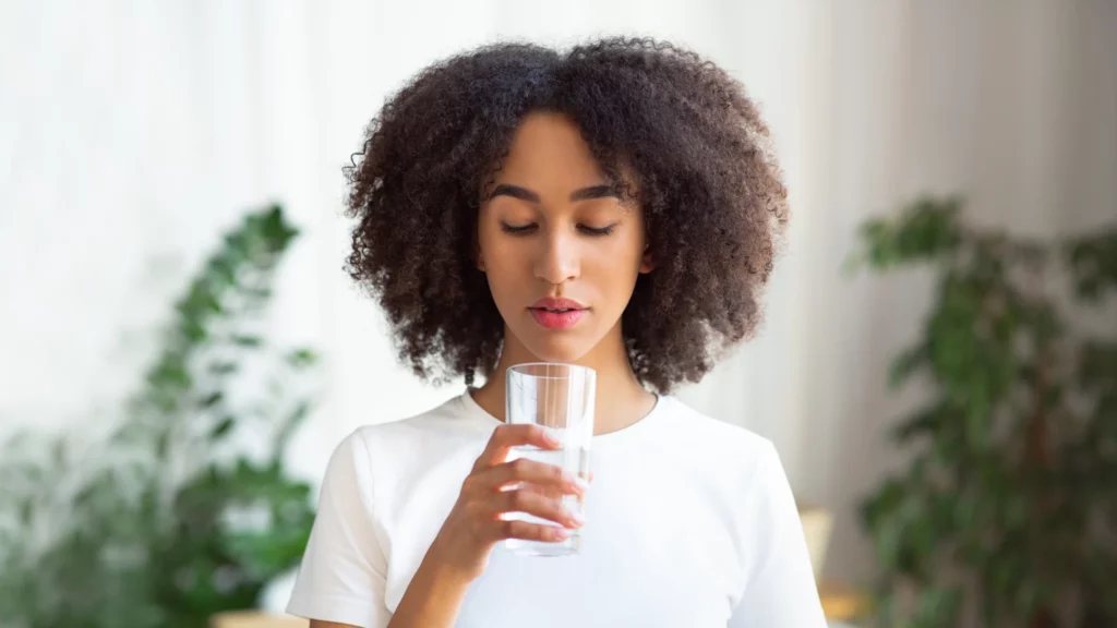 African American woman holding glass of water.