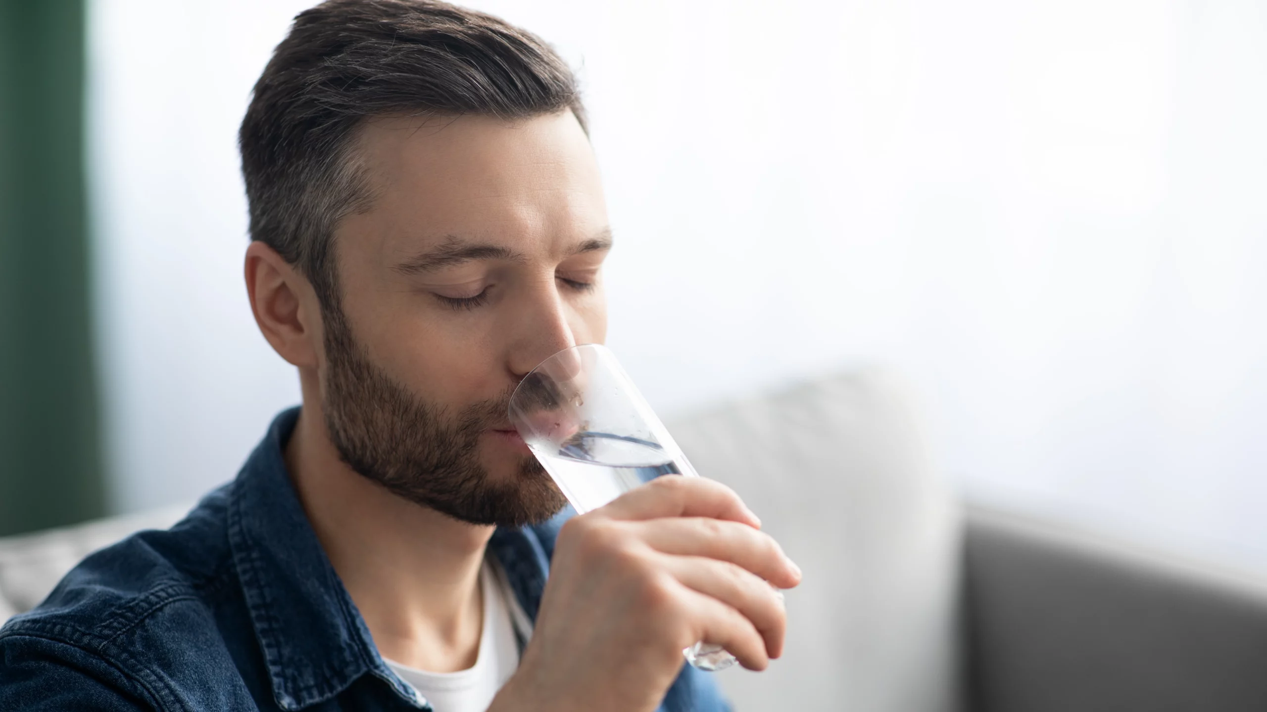 Man with beard drinking a glass of water.