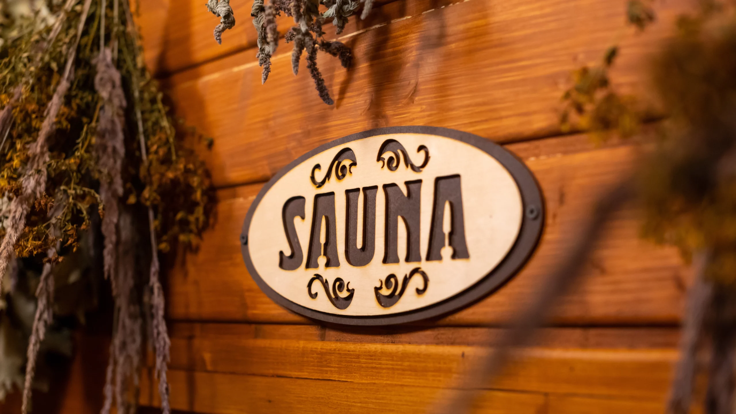 Dried herbs hanging above and beside wooden sauna sign.
