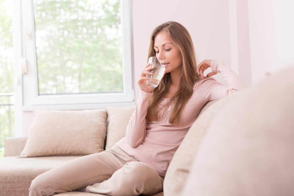 woman drinking a glass of water on the couch