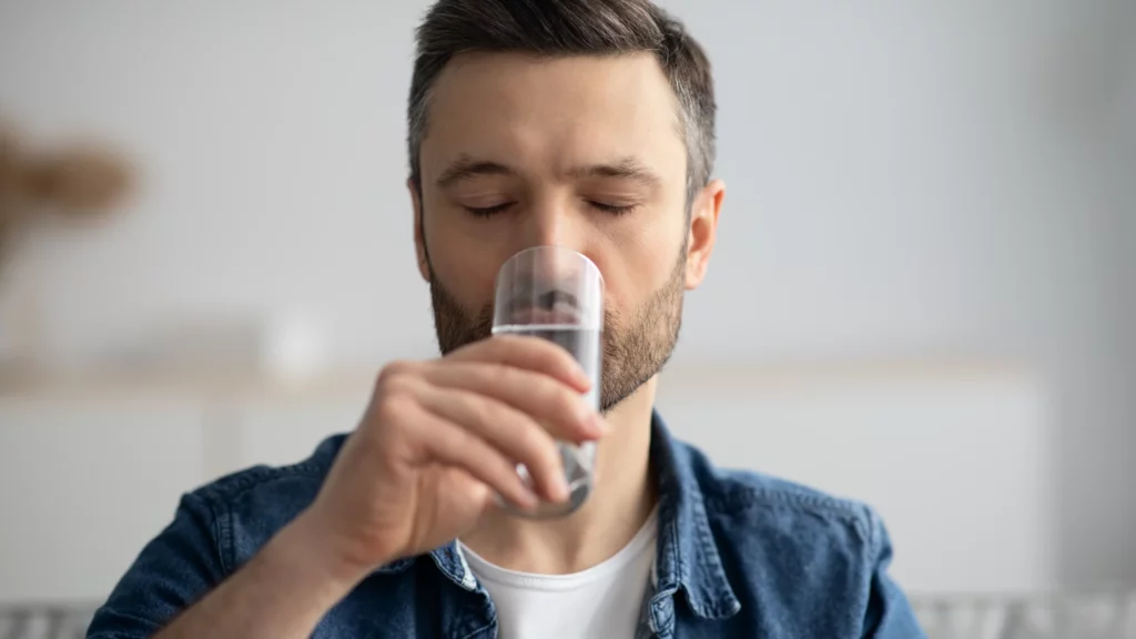 Closeup of a man with beard drinking a glass of water.
