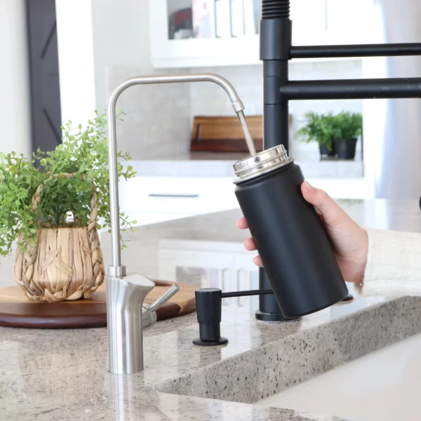A black water bottle being filled with water from the best undercounter water filter, the UltraLux Water Machine