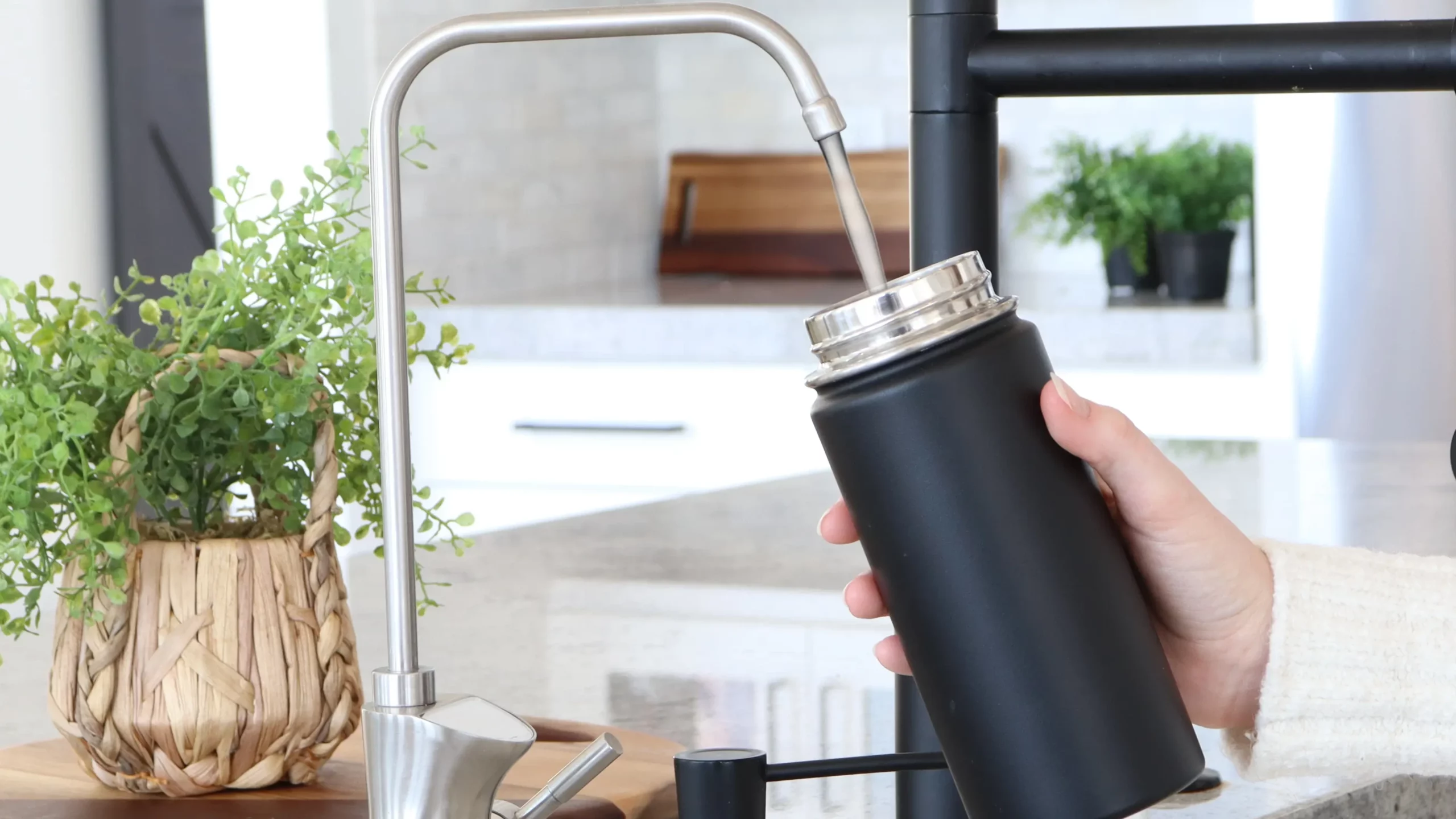 Person filling up a black water bottle with the UltraLux Water Faucet.